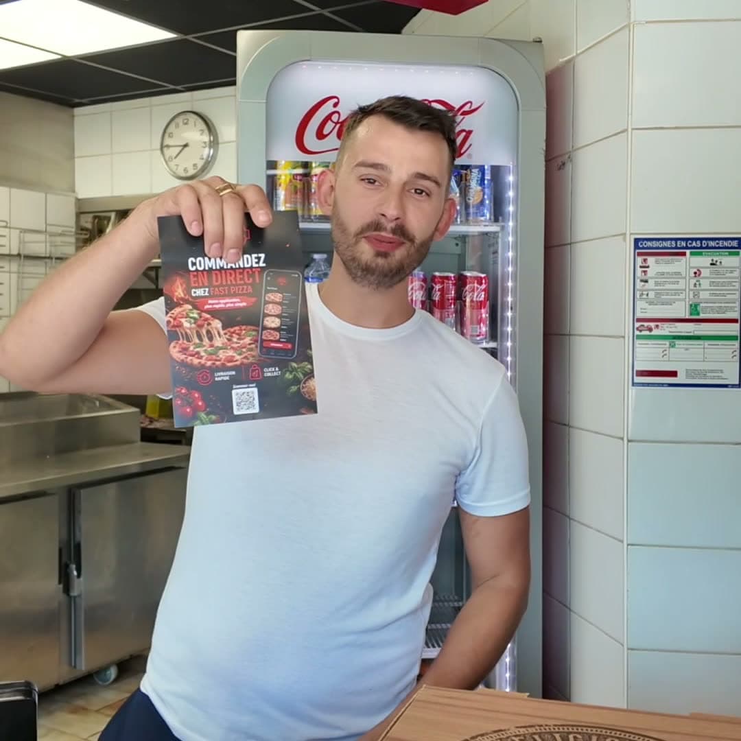 Jérémy Durandeau derrière le comptoir de Fast Pizza, le flyer « Commandez en direct » à la main